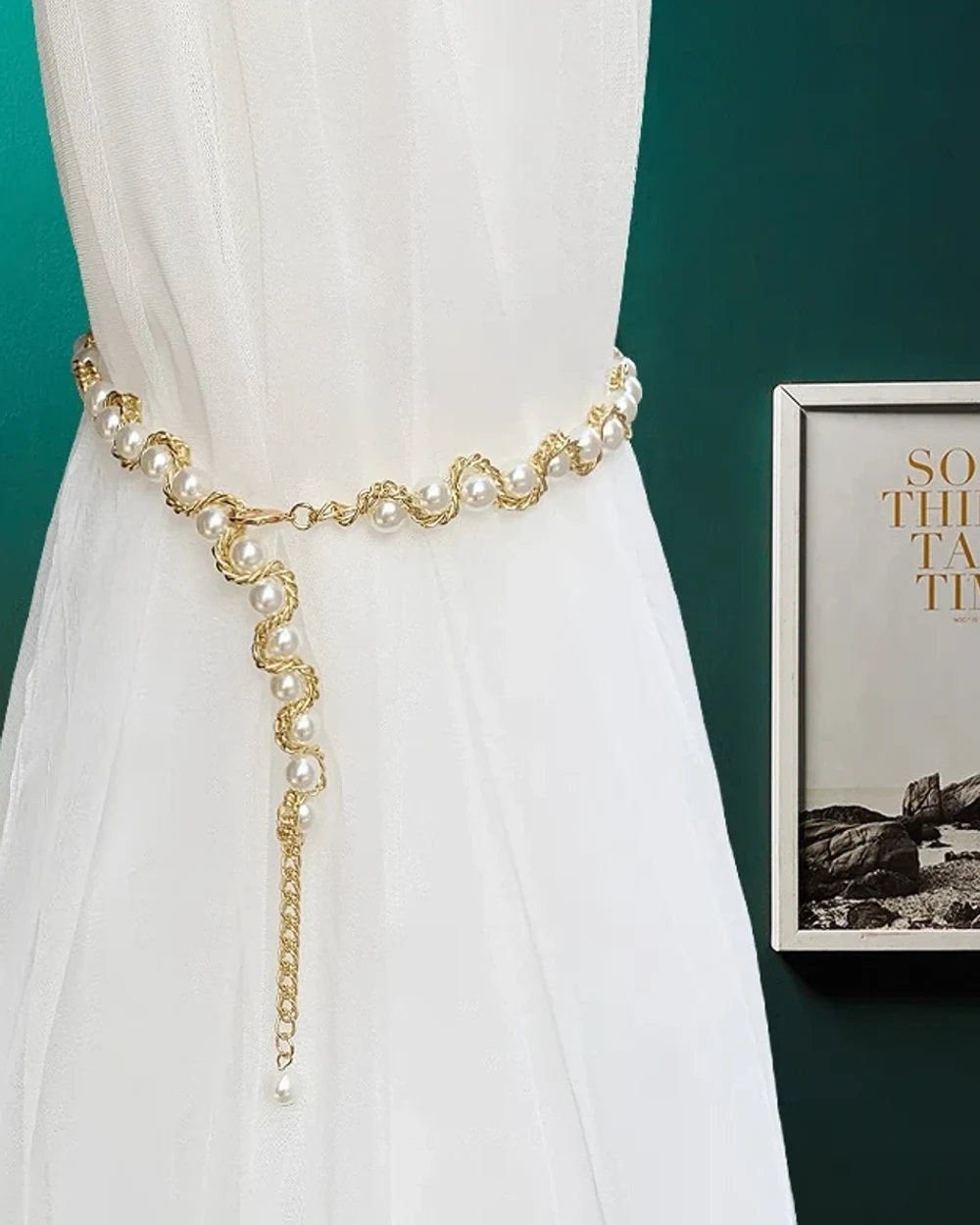Pearl-look beads entwined in a gold-tone chain, gathering a white sheer curtain with a long pendant tail.
