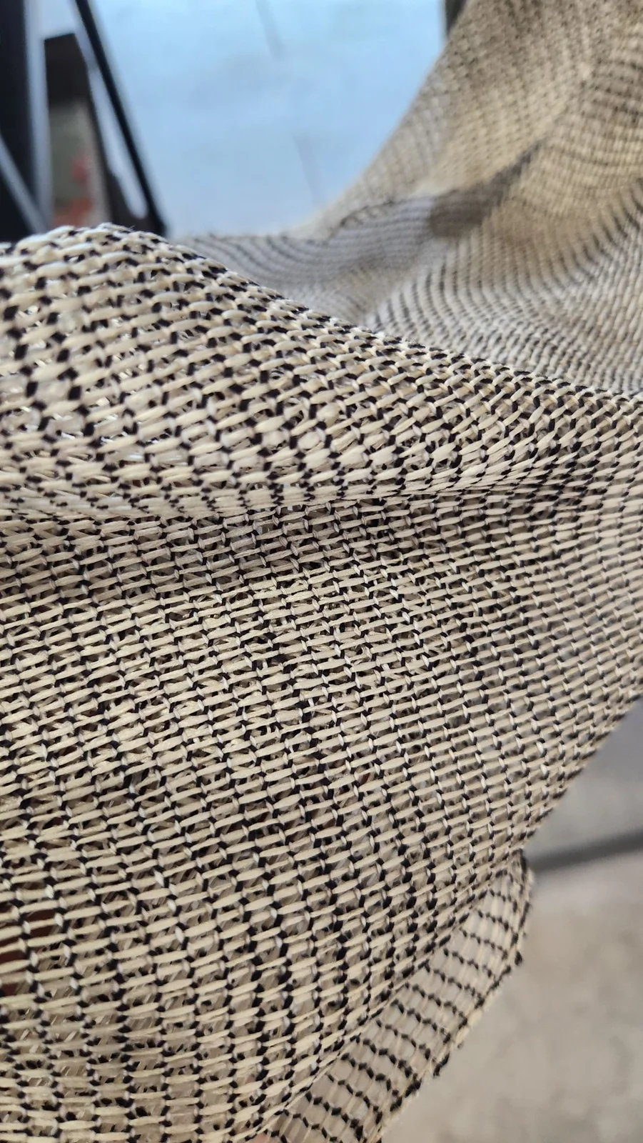 Close-up of open black-and-cream textured weave held by a window.
