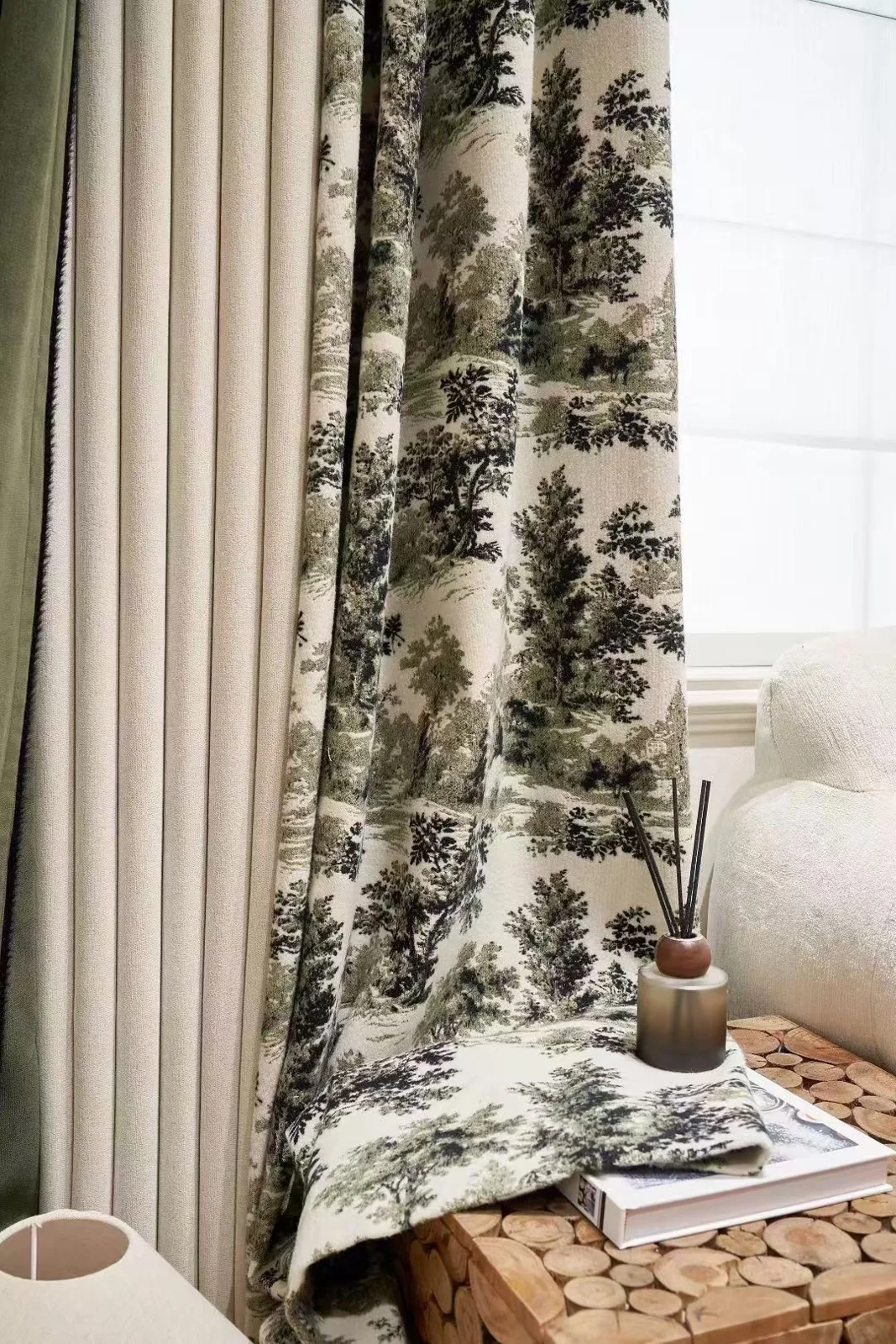 Black-and-cream scenic tree/woodland toile-style curtain beside plain neutral drapery.