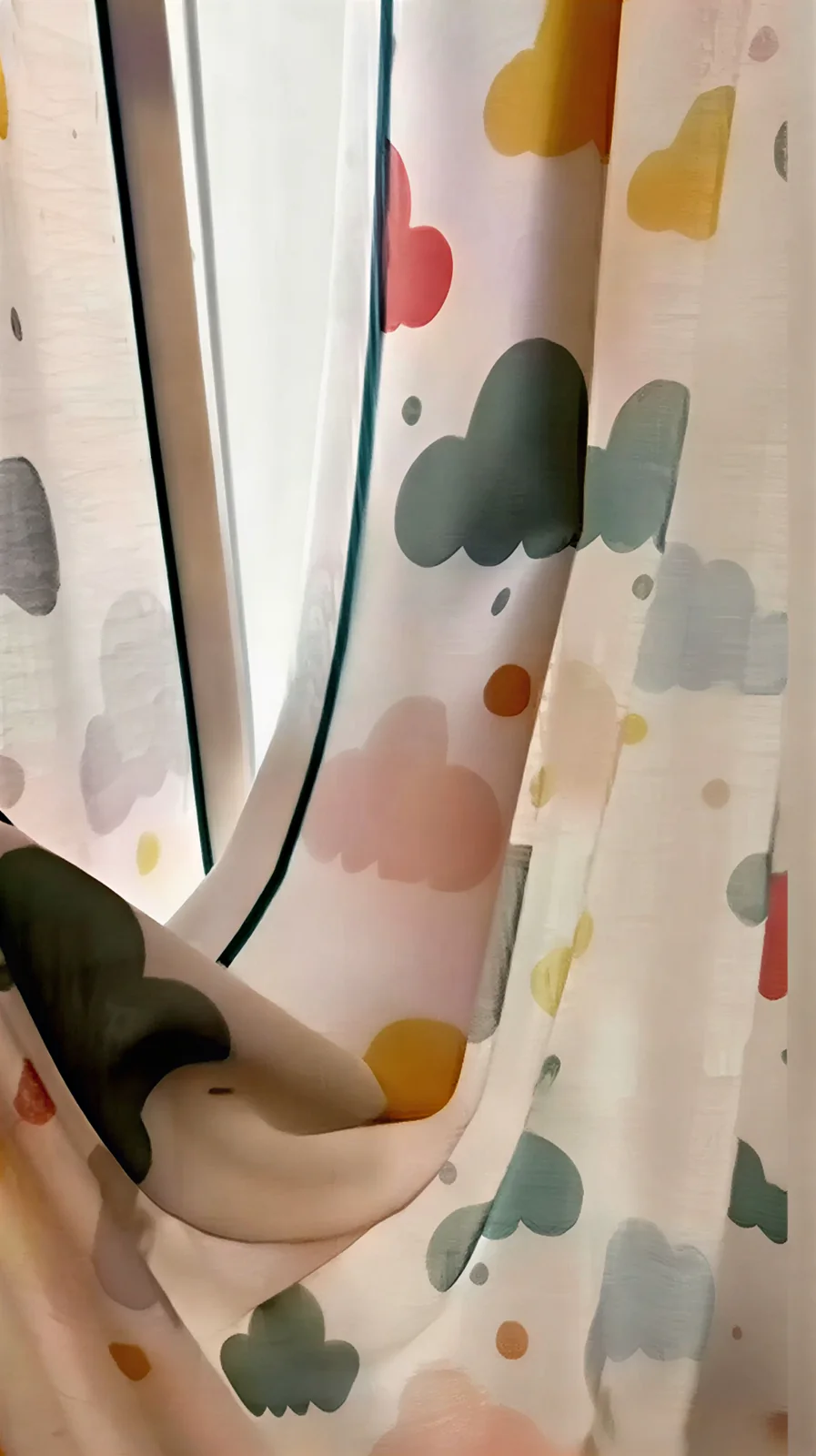 Playful curtain with pastel cloud-like multicolour shapes; close-up of held fabric.