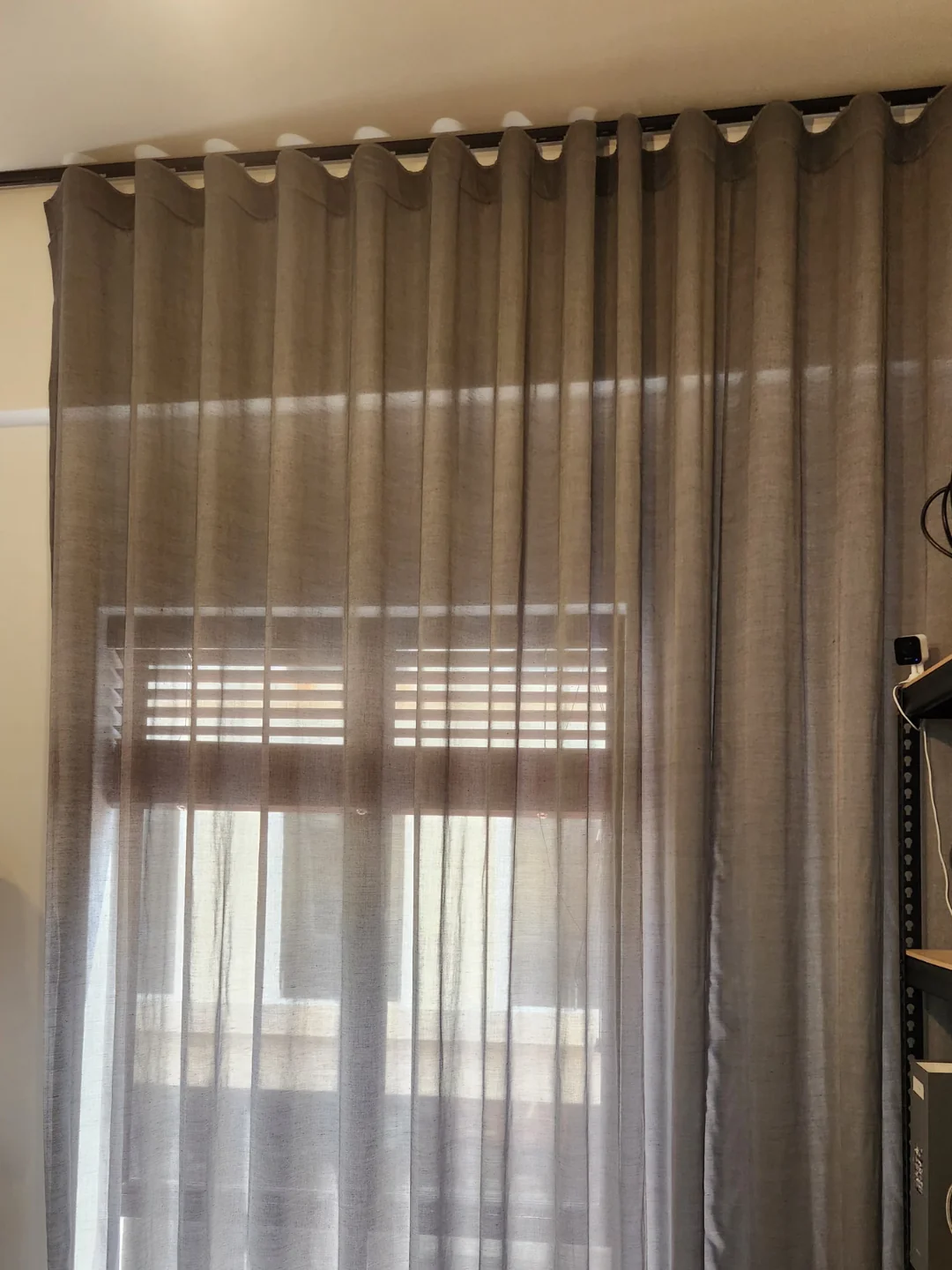 Taupe sheer hanging in continuous rounded ripple waves from a straight dark track; heading visible.