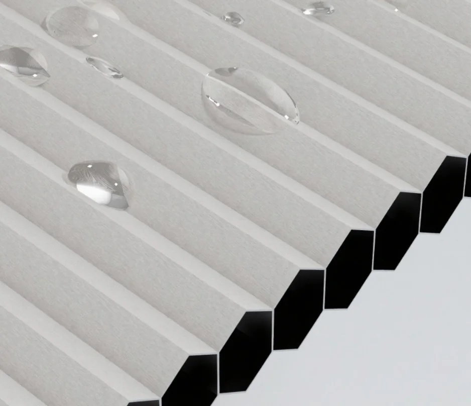 Diagram-like macro view of white hollow cellular shade material showing hexagonal open ends, with water droplets on top.