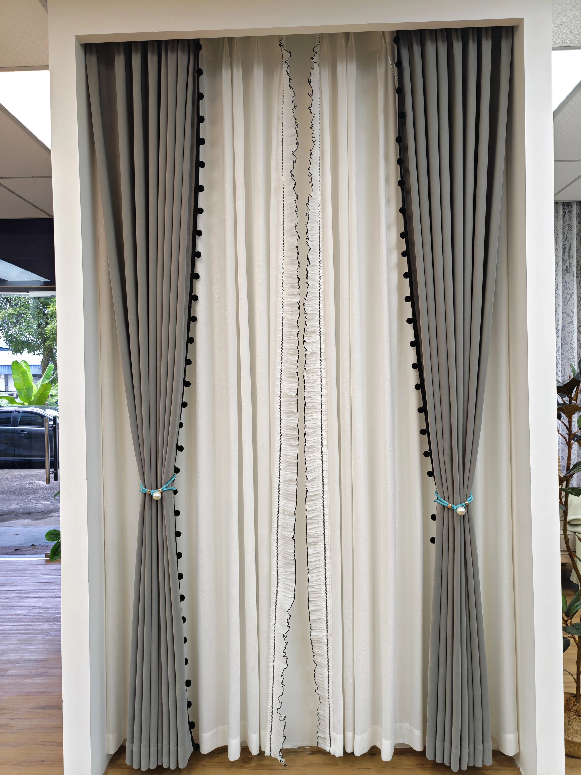 Black pom-poms, outlined ruffle & sheer texture — close-up of the supplied curtain photograph.