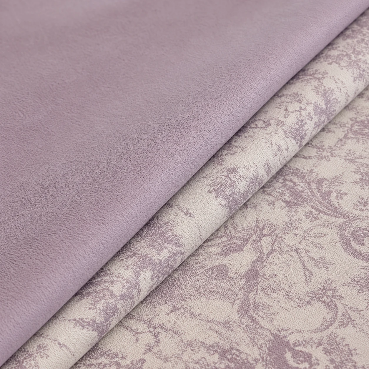 Dusty lilac plain fabric layered diagonally over ivory and lavender patterned cloth.