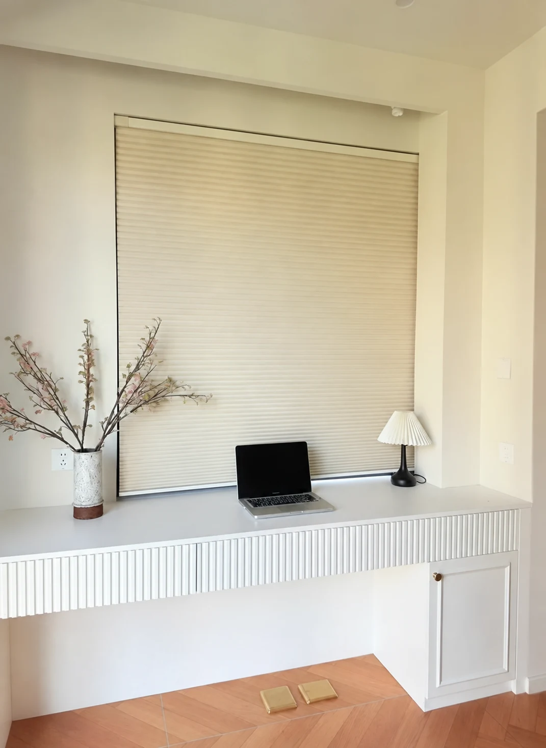 Pale finely pleated blind over a compact desk alcove; small four-point AI-generation-style sparkle visible at lower right.