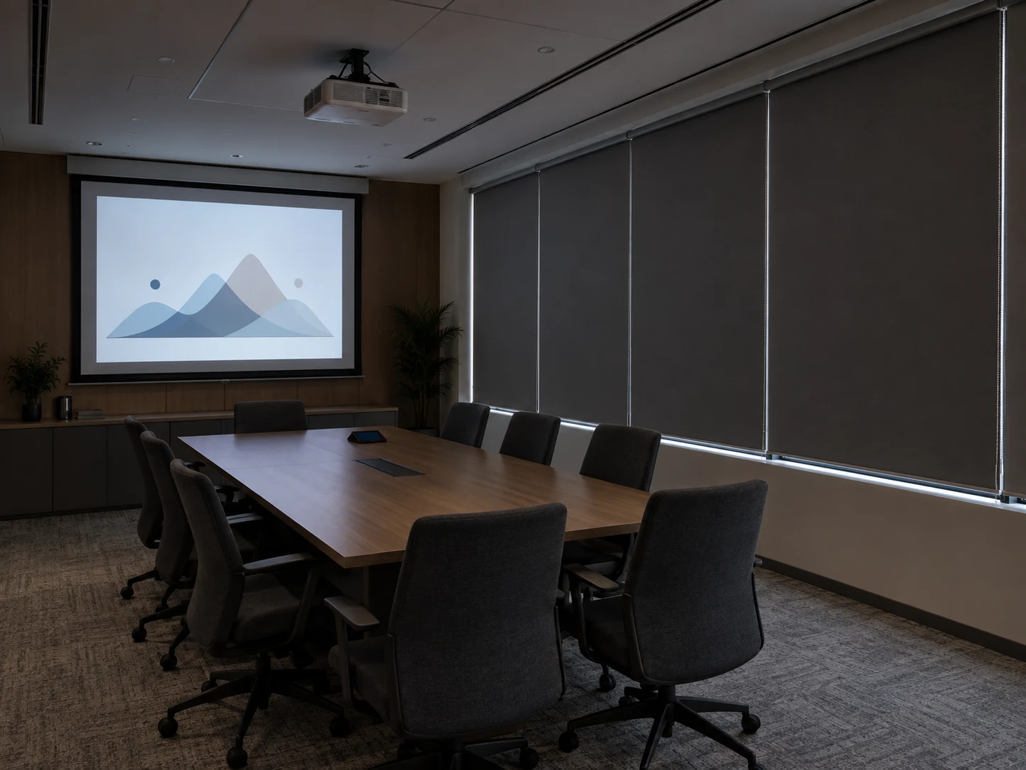 Commercial presentation room with a projector, screen, meeting table and fully lowered opaque roller blinds; narrow daylight gaps are visible around the blind edges.
