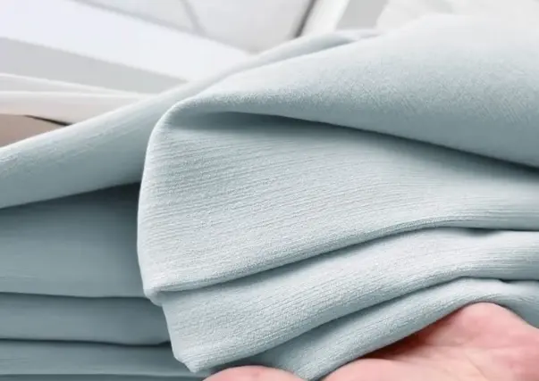 Soft, light blue folded textile swatch – versatile fabric for curtains, upholstery, or throws in minimalist interior design