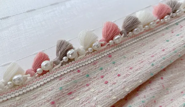 Textured fabric with pom-pom trim – ideal for boho-chic curtains, throws, or accent decor in eclectic interior design