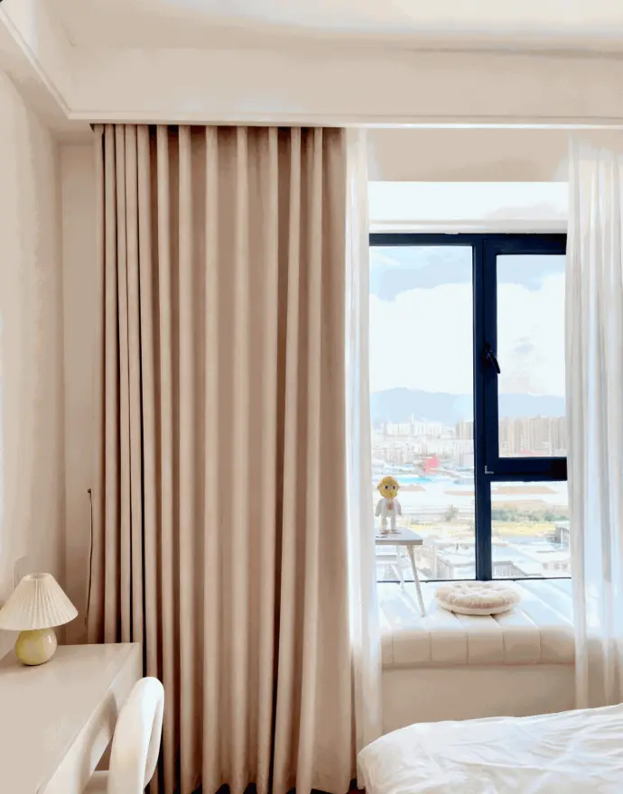 Elegant light beige floor-length curtains framing a bright window in a modern bedroom – soft neutral window treatments for airy, minimalist home decor.